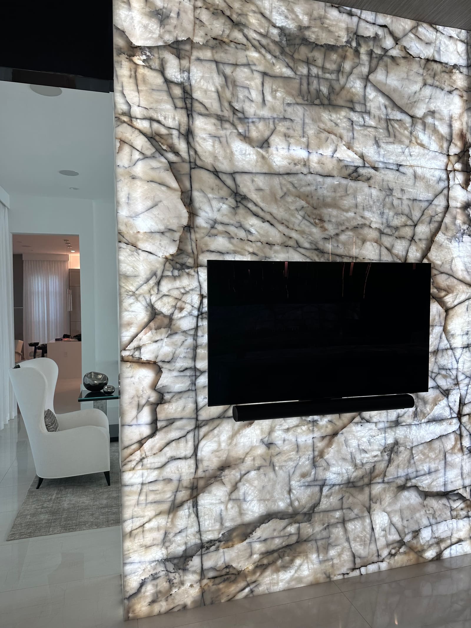 Backlit quartzite feature wall with recessed TV, built by Weston Construction